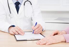 le médecin et le patient discutent de quelque chose, juste les mains à la table, l'assurance médicale. photo