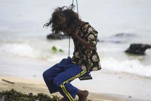 sorong, papouasie occidentale, indonésie, 12 décembre 2021. une jeune fille jouant de la balançoire au bord de la plage photo