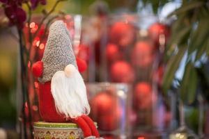 peluche de noël père noël sur une boîte avec un cadeau sur fond de boules rouges photo