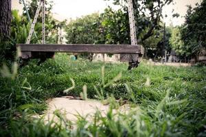 Vieille balançoire vintage en bois suspendue à un grand arbre dans le jardin avec fond d'herbe verte photo