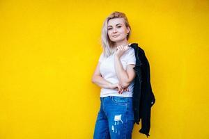 femme en veste noire souriante posant sur fond de mur jaune photo