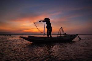 pêcheur asiatique avec son bateau en bois dans la rivière nature tôt le matin avant le lever du soleil photo