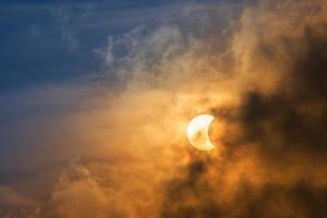 la lune couvrant le soleil dans une éclipse partielle avec un nuage dramatique. formation scientifique, phénomène astronomique. fond de la nature. photo