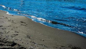 plage de sable volcanique noir et mer photo