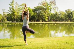 jeune femme asiatique yoga à l'extérieur reste calme et médite tout en pratiquant le yoga pour explorer la paix intérieure. le yoga a de bons avantages pour la santé près du lac du parc. concept de sport et de mode de vie sain.