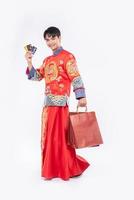 l'homme porte un costume cheongsam obtient beaucoup de choses en utilisant une carte de crédit au nouvel an chinois photo
