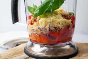 ingrédients pour le pesto de poivre dans un mélangeur. préparation de plats italiens. photo