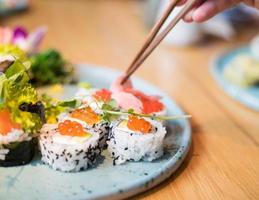 une personne mangeant des sushis dans un restaurant. baguettes visibles atteignant les sushis. photo
