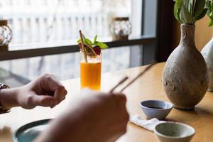 une personne mangeant des sushis dans un restaurant. mains visibles tenant des baguettes. photo