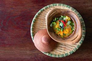 Oeufs pochés au four avec des oignons verts aux épinards et au fromage dans un pot en argile sur une assiette en bambou photo