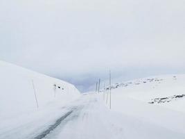 conduire à travers une route enneigée et un paysage en norvège. photo