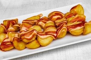 quartiers de pommes de terre avec sauce rouge et blanche. nourriture à Majorque. photo