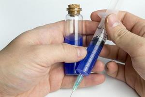 main tenant un tube à essai avec un liquide bleu et une seringue. photo