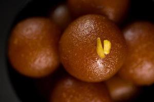 gulab jamun dans un bol sur fond noir. dessert indien ou plat sucré. photo