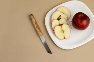 délicieuse pomme et tranche dans une assiette blanche avec couteau et fourchette photo