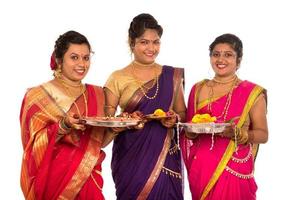 portrait de filles traditionnelles indiennes tenant diya et thali aux fleurs, sœurs célébrant diwali ou deepavali tenant une lampe à huile pendant le festival sur fond blanc photo