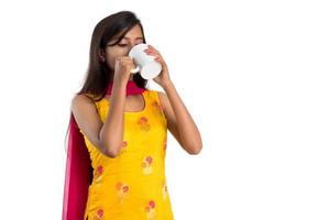 jolie jeune fille avec une tasse de thé ou de café posant sur fond blanc photo