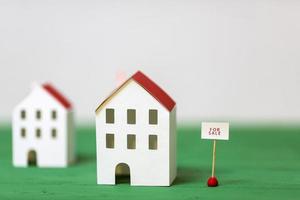 modèle de maison miniature près de l'étiquette de vente bureau texturé vert sur fond blanc