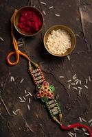 fond raksha bandhan avec un élégant rakhi, des grains de riz et du kumkum. un bracelet indien traditionnel qui est un symbole d'amour entre frères et sœurs. photo