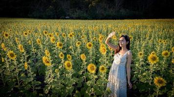 joyeuse fille asiatique joyeuse avec tournesol profitant de la nature et sourire en été dans le champ de tournesol. photo