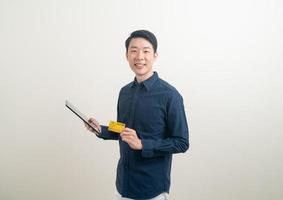 Portrait jeune homme asiatique tenant une carte de crédit et une tablette photo