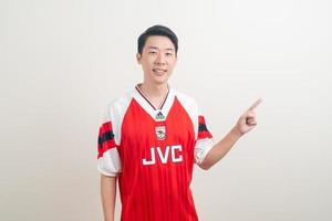 bangkok, thaïlande - 27 novembre 2021 - jeune homme asiatique portant une chemise d'arsenal avec un fond blanc. photo