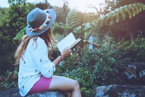 femme asiatique voyage nature. voyager se détendre. étudier lire un livre. éducation à la nature écrivez une note dans un parc public en été. en Thaïlande
