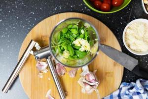 préparer le pesto de basilic. ajouter les ingrédients au mélangeur. feuilles de basilic, ail et noix. photo