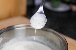 sauce béchamel dégoulinant de la cuillère de cuisine photo