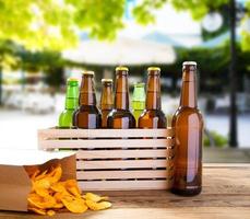 bouteilles de bière et croustilles sur table en bois avec restaurant flou sur fond, bouteille colorée, concept de nourriture et de boisson, mise au point sélective, espace de copie photo