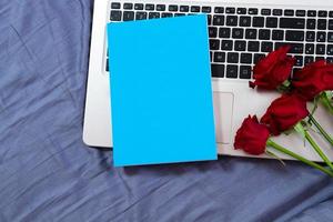 bloc-notes bleu maquette sur ordinateur portable et fond de fleurs rouges se bouchent photo