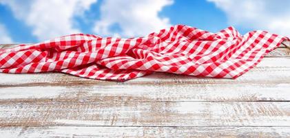 nappe rouge sur une table en bois vide, fond de ciel flou photo