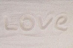 inscription amour sur le sable à la plage. amour écrit dans le sable sur la plage avec vague. photographie de concepts. mise au point sélective photo