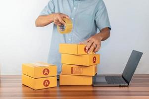 homme utilisant du ruban adhésif pour emballer une boîte pour vendre des affaires en ligne, photo