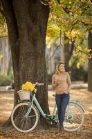 Jeune femme à vélo à l'aide de smartphone dans le parc d'automne photo