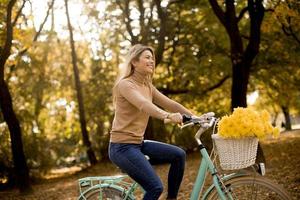 Happy woman riding bicycle in autumn park photo