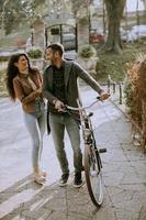 Jeune couple marchant à vélo dans le parc d'automne photo