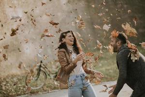 jeune couple s'amusant avec les feuilles d'automne dans le parc photo