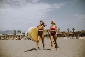 deux jeunes femmes avec paddle board sur la plage un jour d'été photo