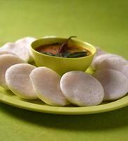 idli avec sambar dans un bol sur fond vert, plat indien nourriture préférée de l'Inde du Sud rava idli ou semoule oisivement ou rava oisivement, servi avec du sambar et du chutney de noix de coco verte. photo