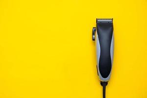 coiffeur tondeuse électrique sur fond jaune. accessoires de coupe de cheveux. vue de dessus. copie, espace vide pour le texte photo