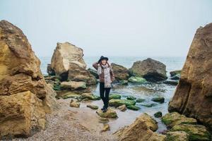 femme dans un chapeau et une écharpe debout sur un rocher contre une belle mer à l'horizon photo