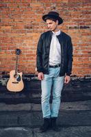 homme avec une guitare sur le fond d'un mur de briques photo