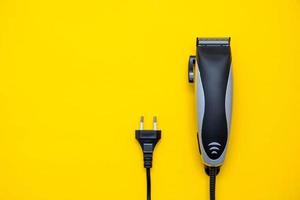 coiffeur tondeuse électrique sur fond jaune. accessoires de coupe de cheveux. vue de dessus. copie, espace vide pour le texte photo