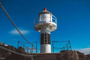 phare sur la jetée sur fond de montagnes et de ciel bleu sur les îles Lofoten. place pour le texte ou la publicité photo