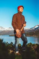 jeune homme est debout avec une guitare sur fond de montagnes et de lac. place pour le texte ou la publicité photo