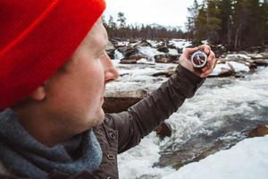 homme voyageur tenant une boussole sur fond de rivière de montagne, de rochers et de forêt. tirer de dos. place pour le texte ou la publicité photo