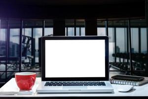 vue de face d'une tasse et d'un ordinateur portable, d'un smartphone et d'une tablette sur une table au bureau photo