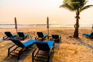 chaise parapluie plage avec palmier et plage de la mer aux heures de lever du soleil photo