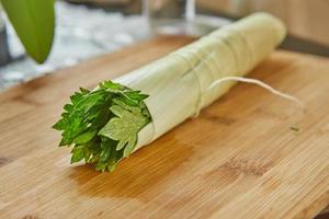 un bouquet de verdure prêt à l'emploi se trouve sur une planche de bois dans la cuisine, pour dresser le plat photo